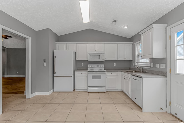 kitchen with white appliances, lofted ceiling, a textured ceiling, white cabinets, and a sink