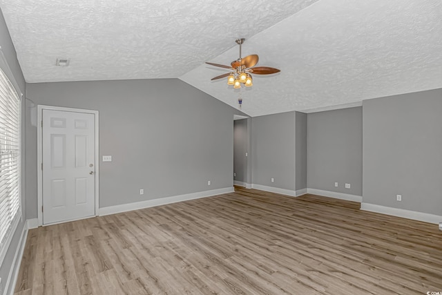 unfurnished living room with ceiling fan, a textured ceiling, wood finished floors, lofted ceiling, and baseboards