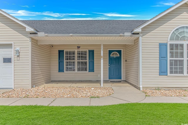 entrance to property with a shingled roof, a garage, and a porch