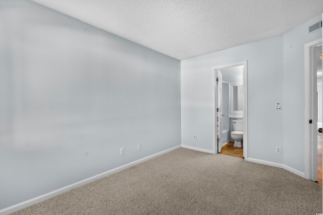 1100 Possum Trot Rd Unit B202, North Myrtle Beach, SC 29582 - unfurnished bedroom featuring carpet floors, a textured ceiling, baseboards, and ensuite bathroom