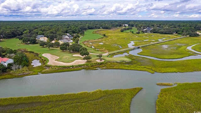 drone / aerial view of a golf club, a large body of water, and a heavily wooded area