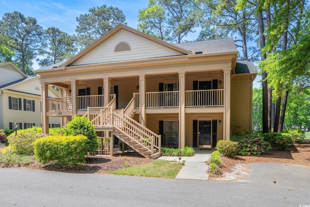 view of front of property featuring stairway, covered porch, and a shingled roof