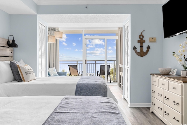 2000 N Ocean Blvd Unit 315, Myrtle Beach, SC 29577 - bedroom featuring access to exterior, light wood-style flooring, a water view, baseboards, and ornamental molding