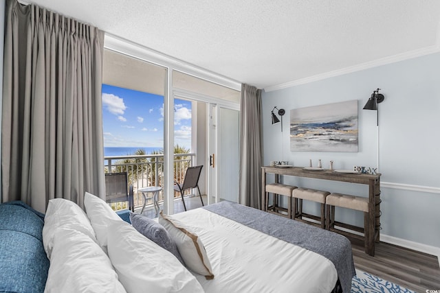 bedroom featuring access to exterior, wood finished floors, a water view, crown molding, and baseboards