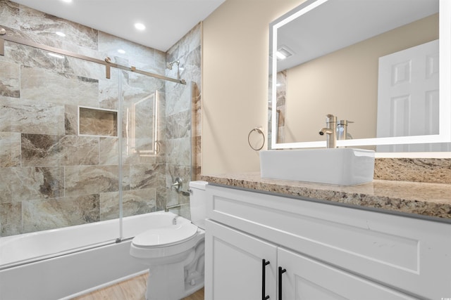 full bathroom featuring toilet, bath / shower combo with glass door, vanity, wood finished floors, and recessed lighting