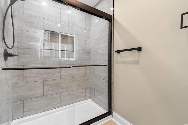 full bath with a shower stall and baseboards