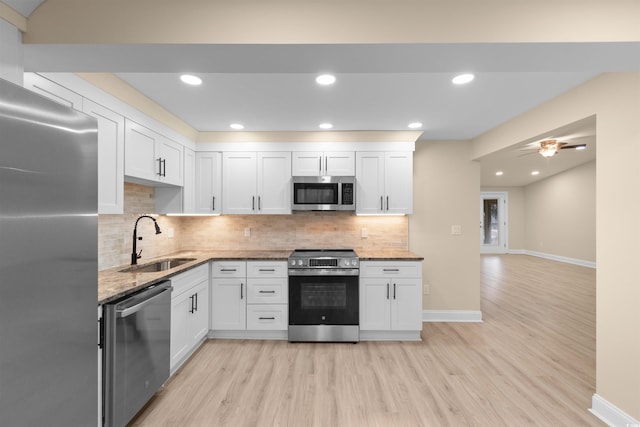 kitchen with stainless steel appliances, a sink, light wood-type flooring, white cabinets, and recessed lighting