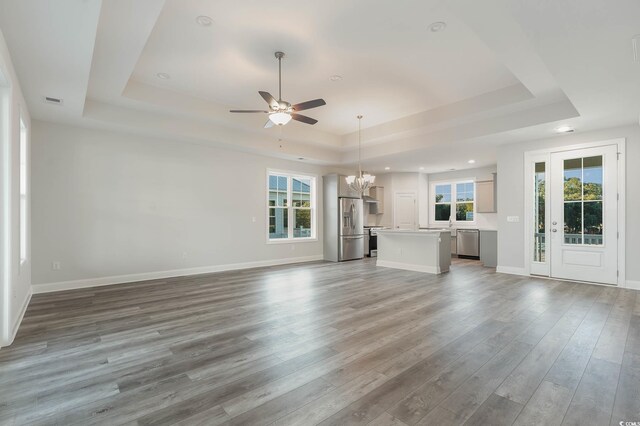 61 Yale Pl, Pawleys Island, SC 29585 - unfurnished living room featuring a tray ceiling, a ceiling fan, wood finished floors, a chandelier, and baseboards
