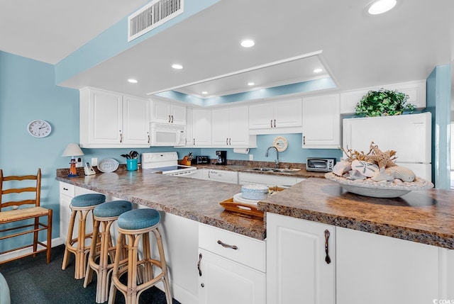 1690 N Waccamaw Dr Unit 103, Garden City Beach, SC 29576 - kitchen with white appliances, a raised ceiling, a sink, dark countertops, and white cabinetry