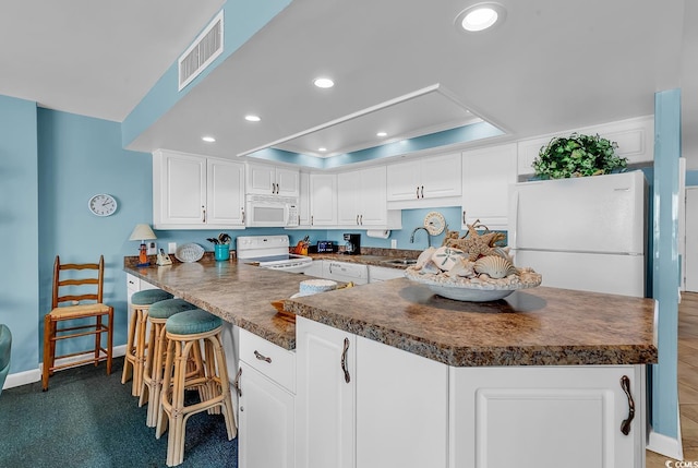1690 N Waccamaw Dr Unit 103, Garden City Beach, SC 29576 - kitchen featuring white appliances, a raised ceiling, dark countertops, recessed lighting, and baseboards