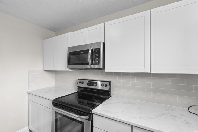 2000 Greens Blvd Unit 40C, Myrtle Beach, SC 29577 - kitchen with appliances with stainless steel finishes, white cabinetry, light stone countertops, and decorative backsplash