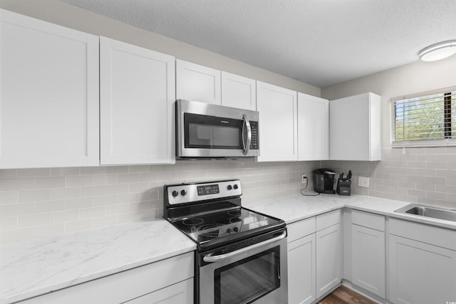 2000 Greens Blvd Unit 40C, Myrtle Beach, SC 29577 - kitchen featuring stainless steel appliances, a textured ceiling, white cabinetry, and decorative backsplash