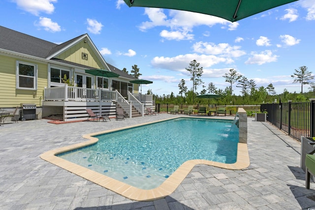 view of swimming pool featuring a deck, a patio, fence, and stairway
