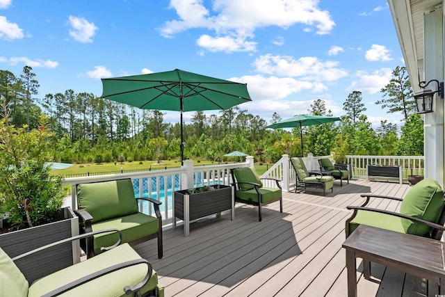 wooden terrace featuring outdoor lounge area, view of wooded area, and a pool