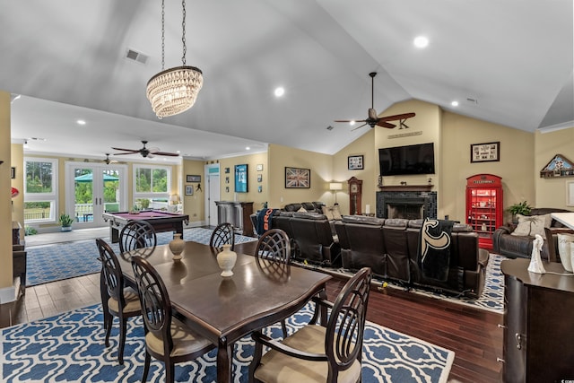 dining area with a ceiling fan, lofted ceiling, wood finished floors, a fireplace, and french doors