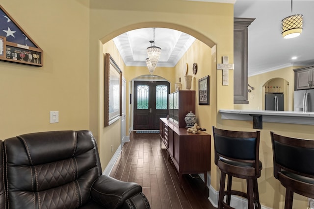 entryway with arched walkways, a chandelier, ornamental molding, dark wood-type flooring, and baseboards