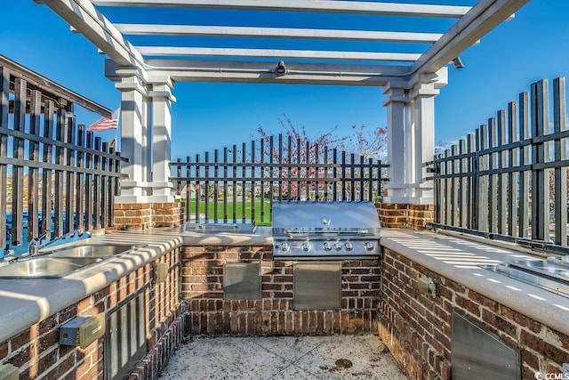 view of patio with exterior kitchen, a grill, a sink, and fence