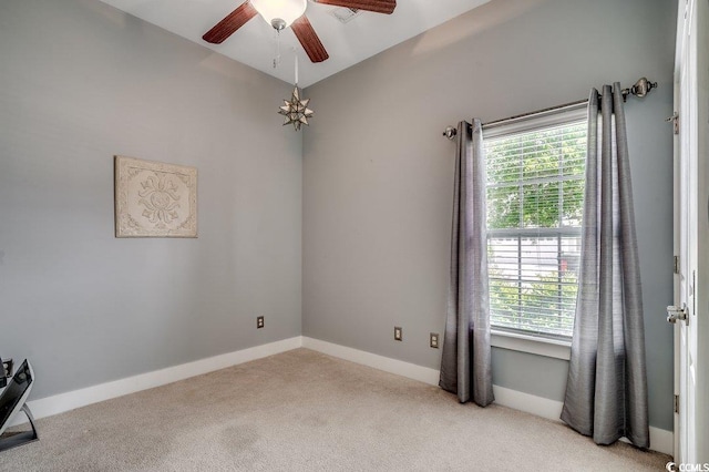 empty room featuring light colored carpet, ceiling fan, and baseboards