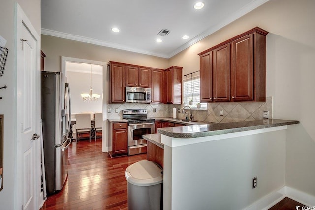 kitchen with stainless steel appliances, a sink, a peninsula, a chandelier, and ornamental molding