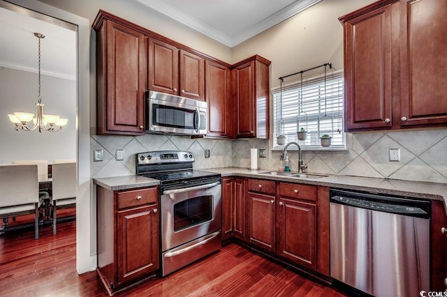 kitchen featuring appliances with stainless steel finishes, a sink, crown molding, a chandelier, and dark wood finished floors