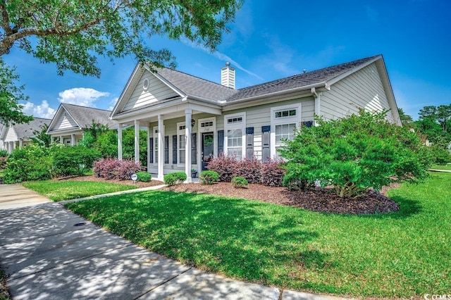 ranch-style home featuring a front yard, covered porch, and a chimney