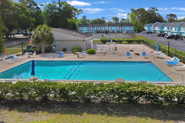 community pool featuring fence, a residential view, and a patio area