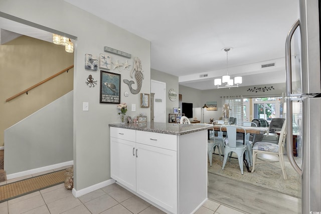 kitchen featuring a chandelier, white cabinets, stone countertops, and a peninsula