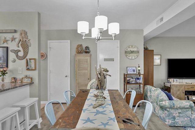 dining space featuring light wood finished floors and a chandelier