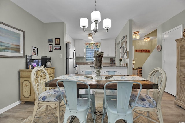 dining area with a chandelier, light wood-type flooring, and baseboards