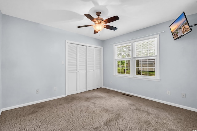 unfurnished bedroom featuring carpet flooring, a closet, baseboards, and a ceiling fan