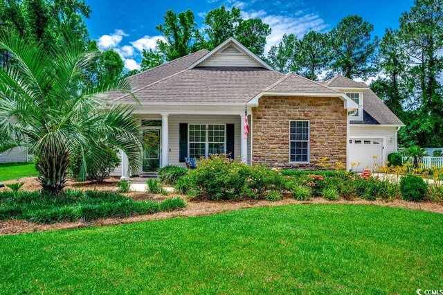 100 Woodlyn Ave, Little River, SC 29566 - view of front of home with stone siding, a front lawn, an attached garage, and a shingled roof