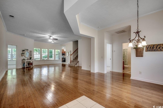 100 Woodlyn Ave, Little River, SC 29566 - unfurnished living room featuring ornamental molding, ceiling fan, stairs, hardwood / wood-style flooring, and a chandelier