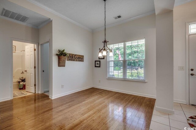 100 Woodlyn Ave, Little River, SC 29566 - unfurnished dining area with ornamental molding, light wood-style floors, baseboards, and a chandelier