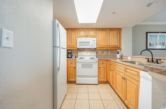 kitchen with white appliances, a sink, decorative backsplash, light tile patterned floors, and crown molding