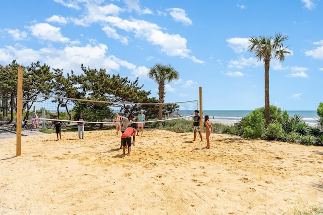 view of home's community featuring volleyball court and view of water and beach