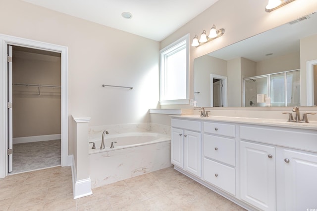 bathroom with a shower stall, double vanity, a garden tub, and a walk in closet