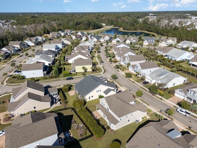 view of property location with nearby suburban area, a forest, and a large body of water
