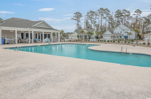 community pool with a patio area and fence