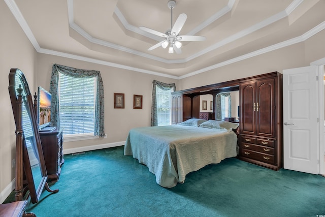 bedroom with a tray ceiling, dark carpet, ornamental molding, a ceiling fan, and baseboards