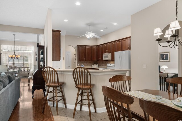 190 Barony Pl, Pawleys Island, SC 29585 - kitchen with white appliances, a chandelier, a breakfast bar area, a peninsula, and backsplash