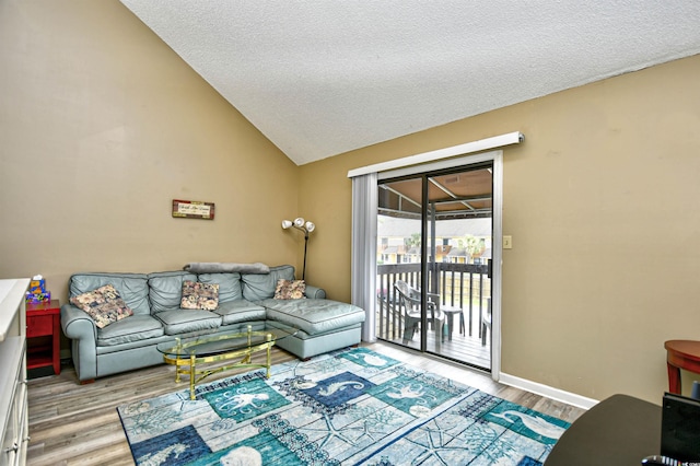 living area with wood finished floors, a textured ceiling, lofted ceiling, and baseboards