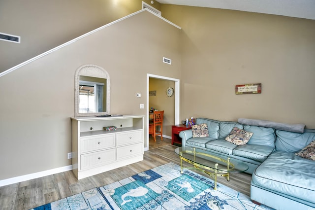 living room with light wood finished floors, baseboards, and high vaulted ceiling