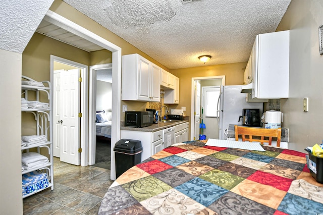 kitchen with black microwave, white cabinetry, dishwasher, a sink, and a textured ceiling