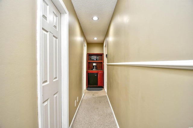 hall featuring baseboards, recessed lighting, a textured ceiling, and carpet