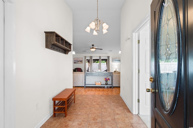 foyer entrance with a chandelier, a ceiling fan, light tile patterned floors, lofted ceiling, and baseboards