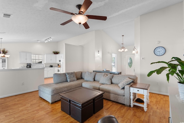 living room with vaulted ceiling, light wood-style flooring, ceiling fan, and a chandelier