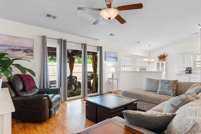 living area with a chandelier, light wood finished floors, vaulted ceiling, and ceiling fan