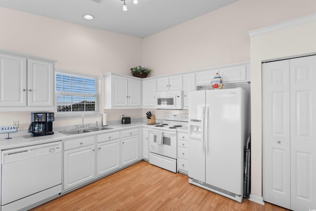 kitchen featuring white appliances, a sink, white cabinets, light countertops, and light wood-style flooring