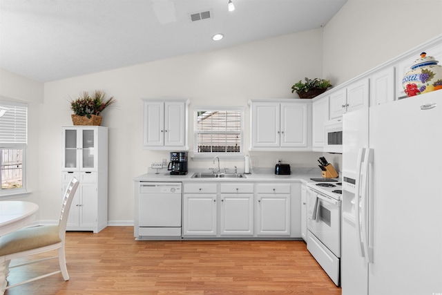 kitchen featuring white appliances, a sink, lofted ceiling, white cabinetry, and plenty of natural light