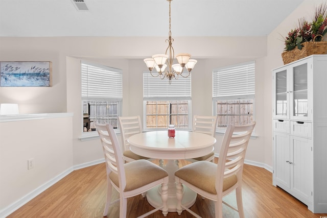 dining space with light wood-style flooring, a chandelier, and baseboards